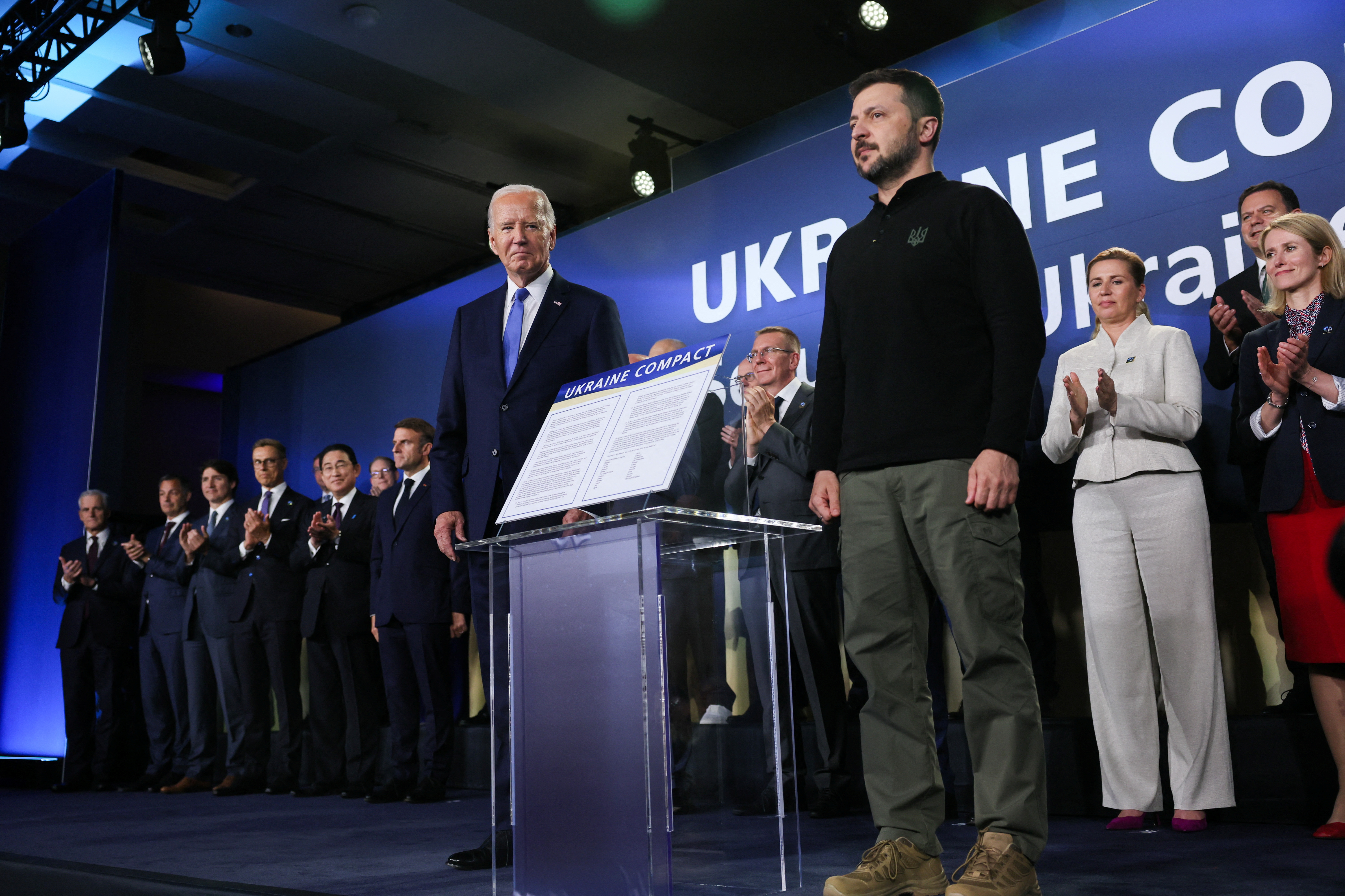 Biden stands on stage with Zelenskyy at a NATO Ukraine council stage.