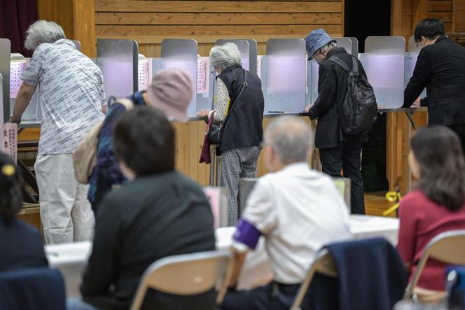 Voters vote during the early legislative elections, at a polling station in Tokyo, October 27, 2024. 