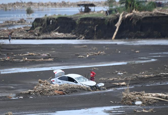 A man stands near a destroyed vehicle washed away by rains in Laurel town, Batangas province, October 30, 2024. 