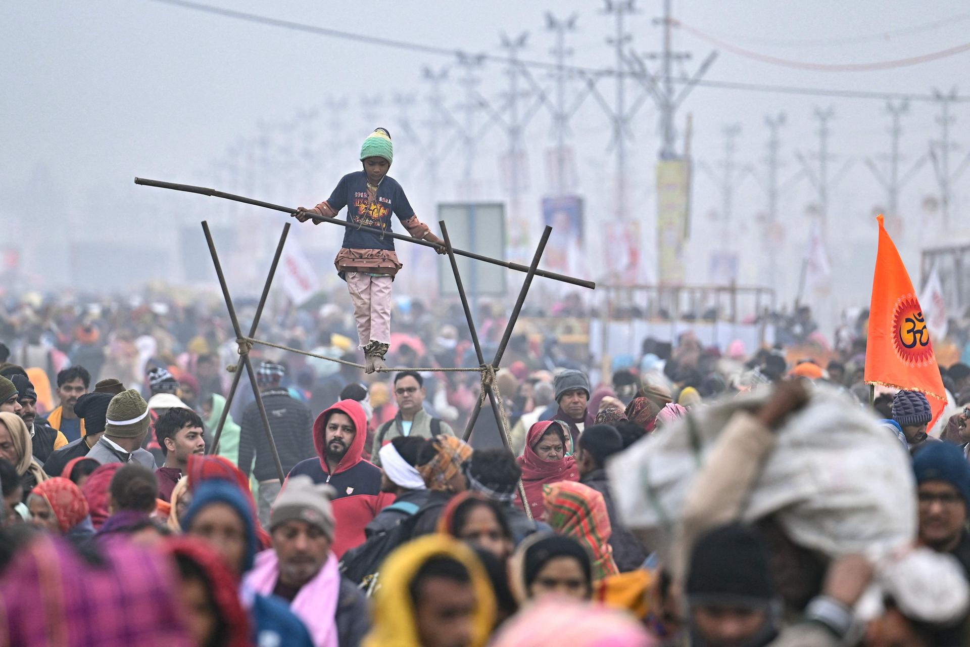 A child produces a balancingist number, in the middle of the crowd of the Maha Kumbh Mela festival in Prayagraj on January 13, 2025.