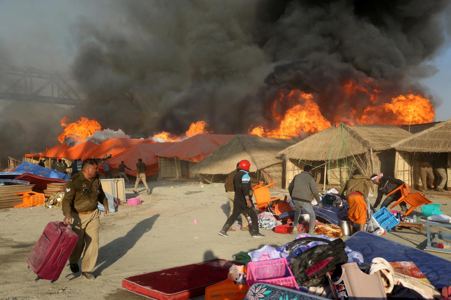 Police and pilgrims evacuate luggage and tents threatened by an accidental fire, at the Maha Kumbh Mela festival in Prayagraj, India, January 19, 2025.