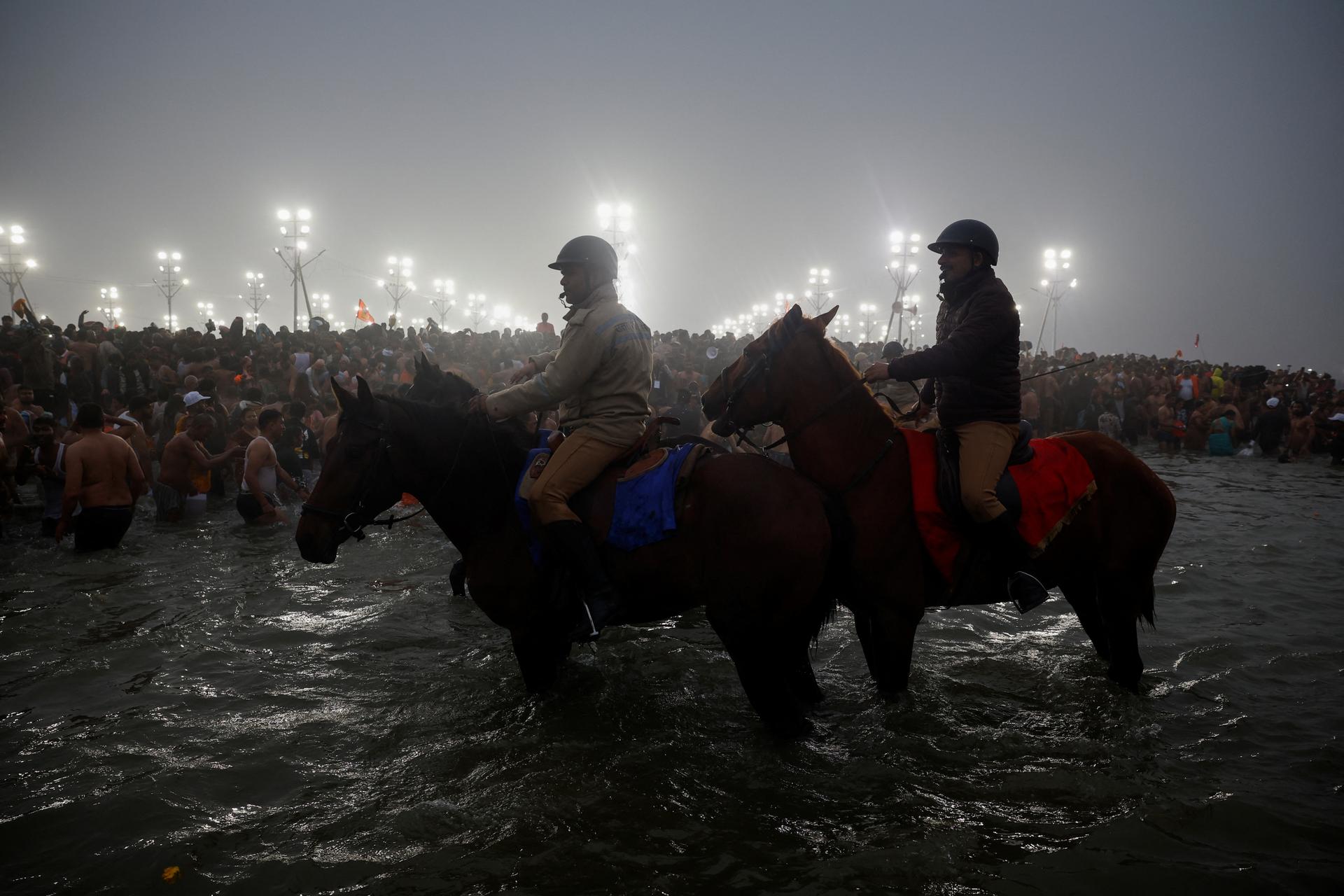 Police on horseback monitors the crowd on the banks of the Ganges in Prayagraj, India, January 14, 2025.